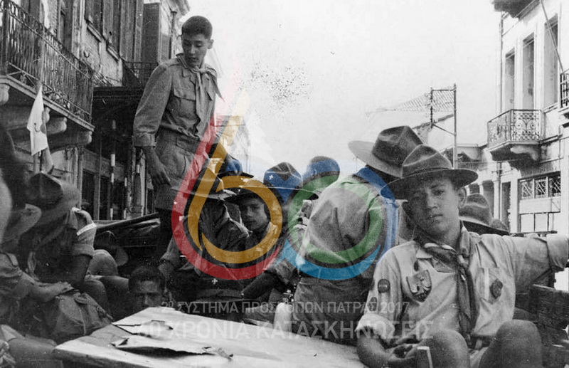 1959, 10η Κατασκήνωση Ομάδας του 2ου Συστήματος Προσκόπων Πάτρας στου Μίχα. Συνέχεια από την προηγούμενη φωτογραφία, όπου πρόσκοποι και υλικό πάνω στο φορτηγό οδεύουν για την κατασκήνωση. Σε πρώτο πλάνο ο Κώστας Ηλιόπουλος "Κόκκορας", δίπλα ο Πέτρος Καθρέπτας και ο Γιάννης Μάνος και όρθιος ο Βασίλης Γιαννακούλιας. Τέρμα αριστερά διακρίνεται το κοντάρι της Ενωμοτίας Λεόντων.